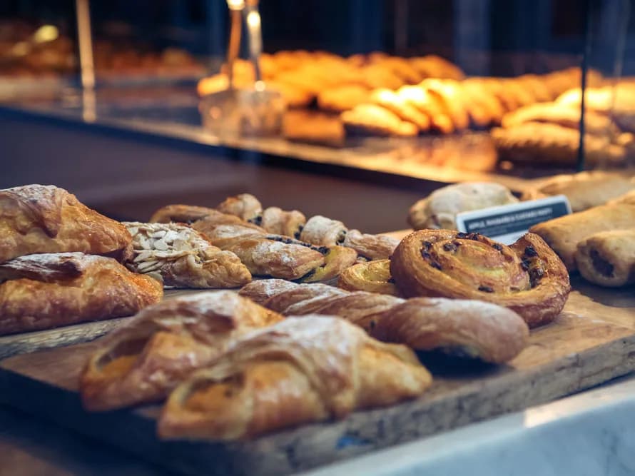 Bandeja de folhados e croissants numa vitrine iluminada de padaria